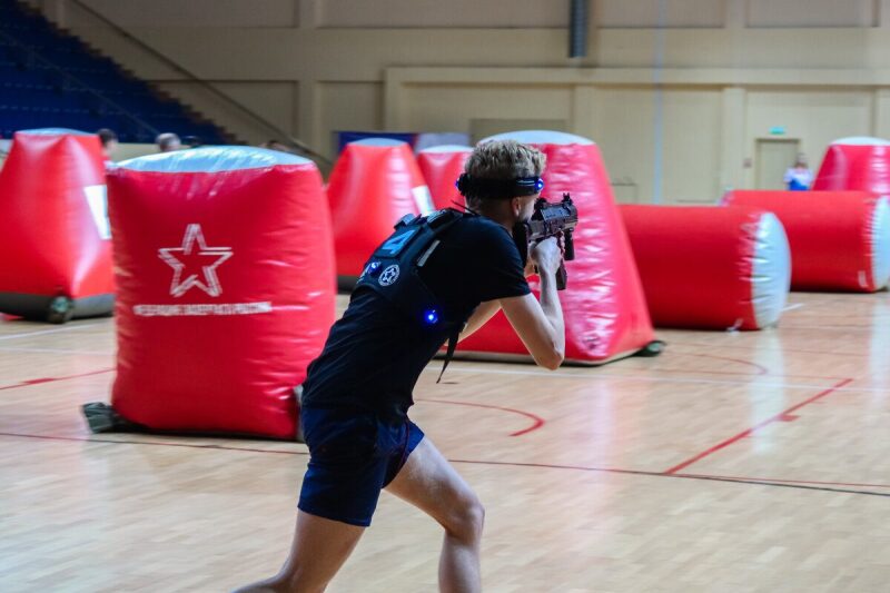 Игрок LASERWAR в движении с оружием между красными укрытиями.